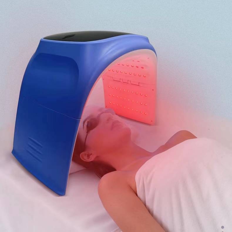 User relaxing under the Omega PDT Light with red LED lights during a facial treatment.