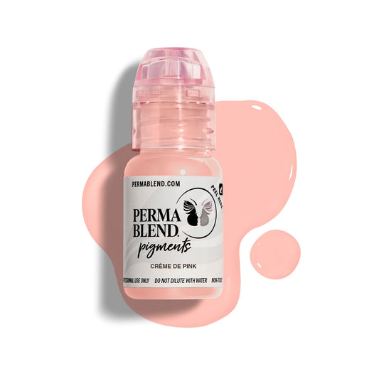 A bottle of Permablend Crème de Pink pigment, showcasing a light pink color with a glossy cap, set against a light backdrop and surrounded by spilled pigment.